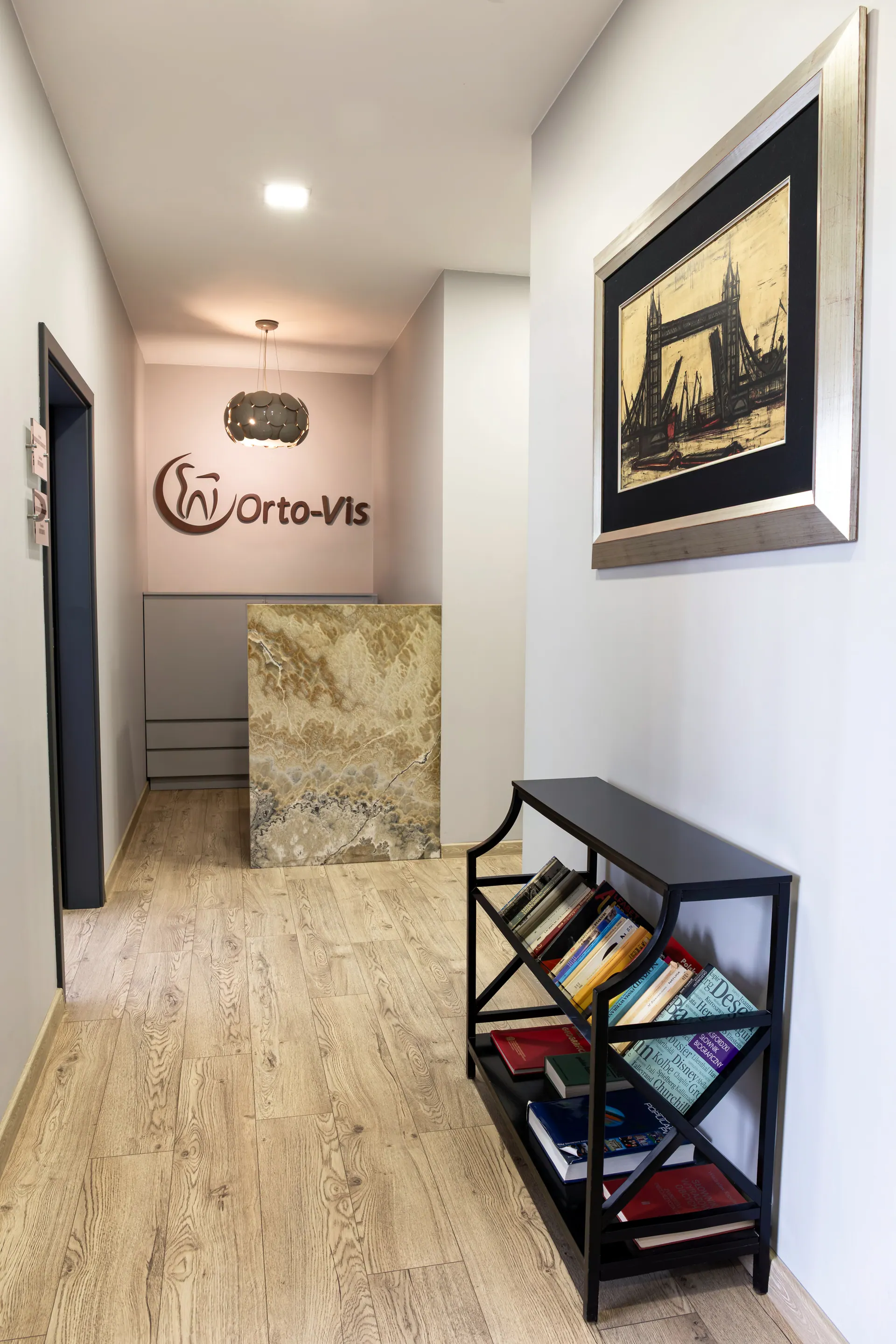 Corridor at Orto-vis leading to reception with the clinic logo on the wall.