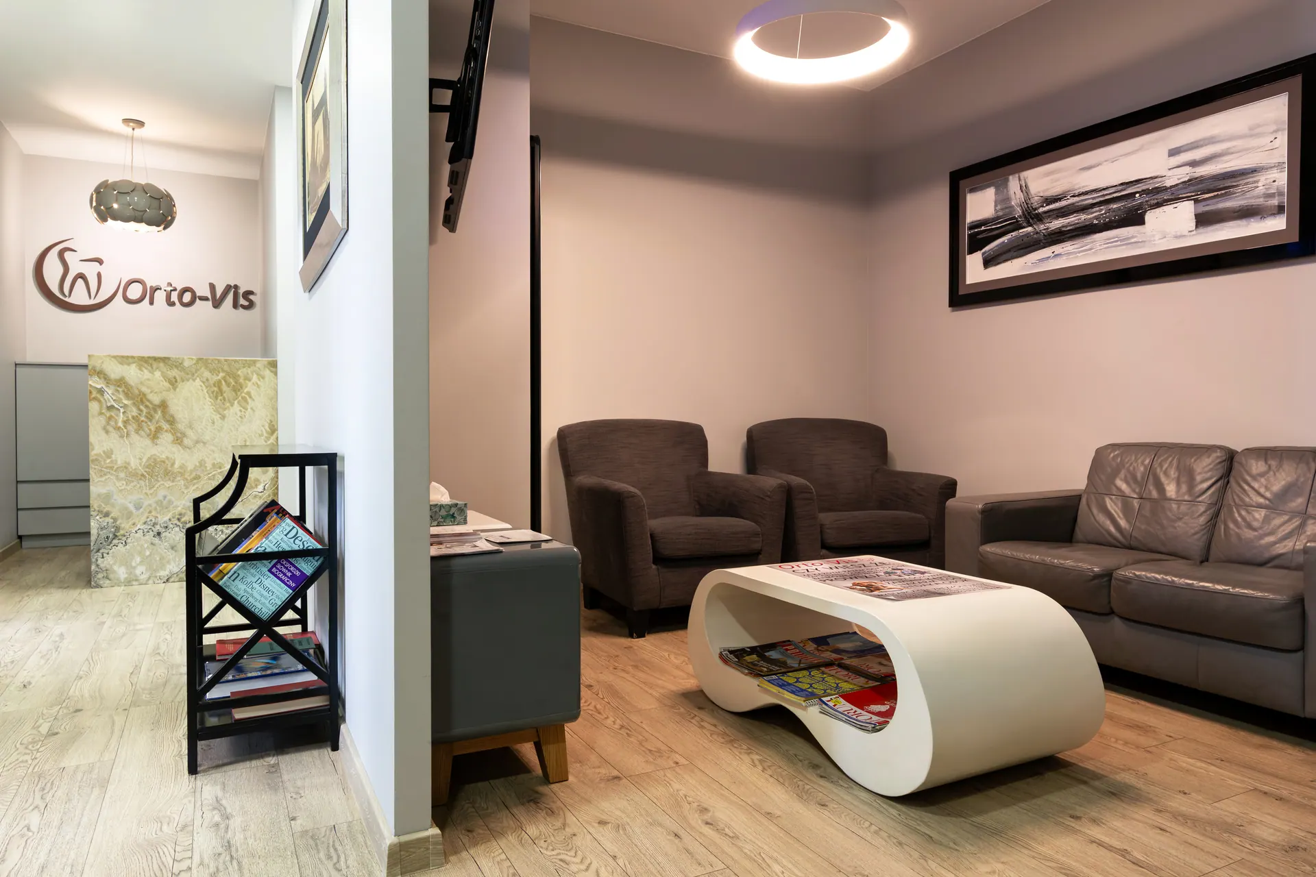 Reception and waiting area at Orto-vis — wall logo, stone counter and seating for patients.