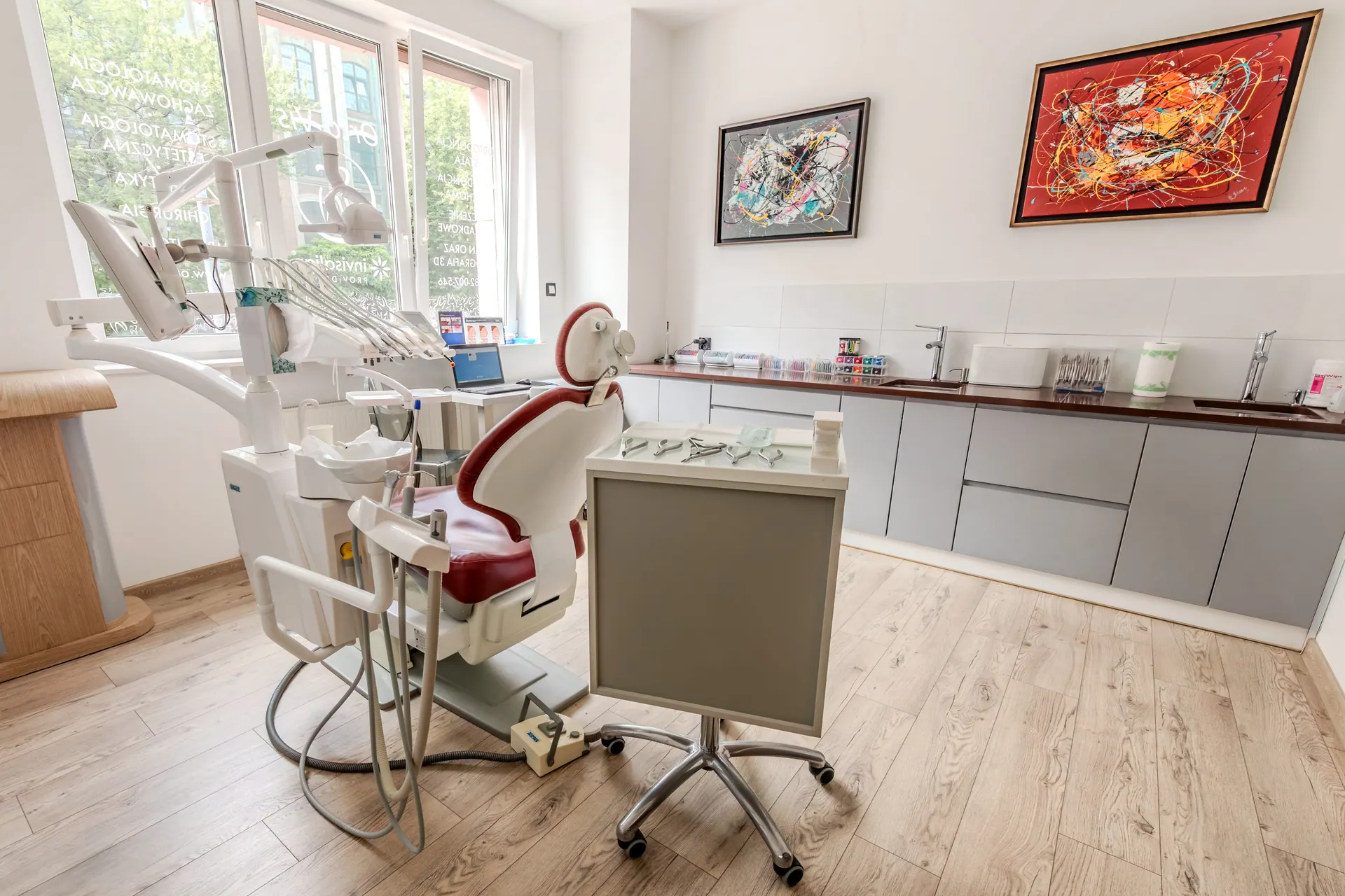 Spacious Orto-vis treatment room with cabinetry, a dental unit and a view of greenery.